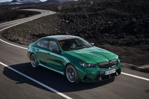 Zielony BMW M5 2025 pędzi po krętej drodze wśród wulkanicznych krajobrazów.