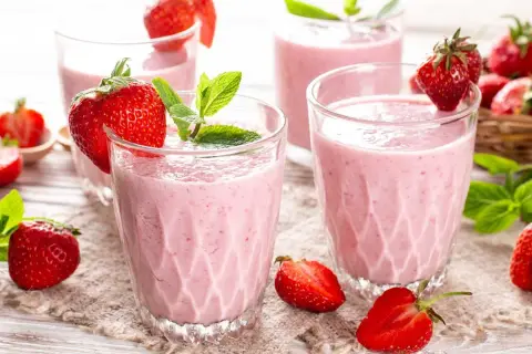 Batidos de fresa en vasos con fresas frescas y hojas de menta.