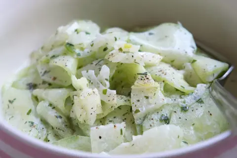 Cremiger Gurkensalat, ein einfaches und erfrischendes gurkensalat rezept, garniert mit Kräutern und Pfeffer.
