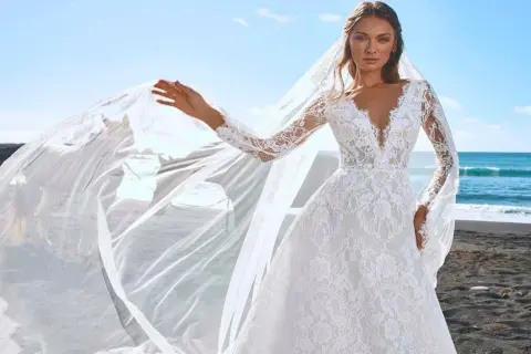 Une mariée sur une plage de sable noir, sa robe en dentelle et son voile flottant au vent, comme une cascade du voile de la mariée.