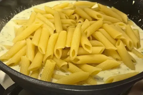 Smażony makaron penne w kremowym sosie z ziołami, gotowy do podania.
