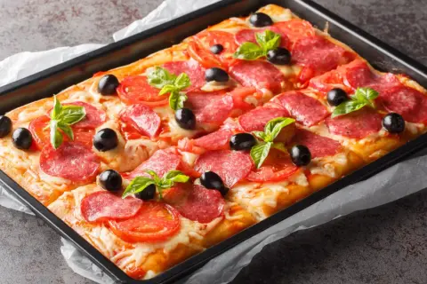 Chrupiąca pizza na cieście francuskim z salami, pomidorami, oliwkami i bazylią, prosto z blachy.