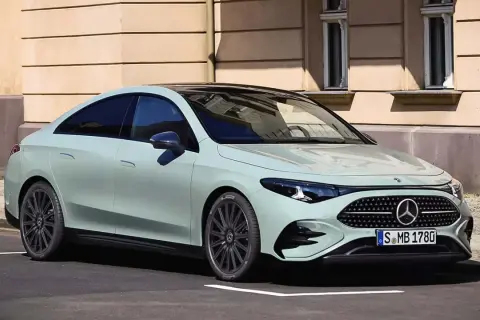 Jasnoszary Mercedes CLA 180 z czarnym dachem stoi na ulicy przed kamienicą.