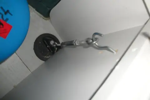Detalle de cómo anclar muebles camper: un gancho metálico sujeto a un punto de anclaje en la pared de una autocaravana.