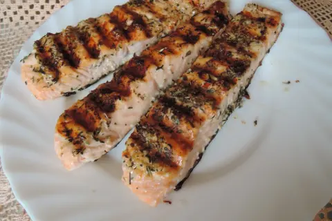 Trzy grillowane filety łososia, przyprawione ziołami, wyglądają apetycznie. Idealna marynata do lososia sprawia, że ryba jest soczysta i aromatyczna.