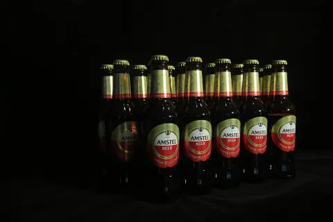 Rząd butelek piwa Amstel na czarnym tle. Czy picie piwa podnosi ciśnienie? To pytanie pozostaje otwarte.