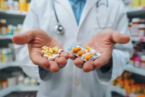Farmaceuta pokazuje leki w dłoniach, sugerując możliwość refundacji.