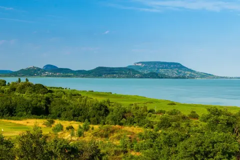 Malowniczy krajobraz z jeziorem Balaton na Węgrzech, zielone wzgórza i błękitne niebo.