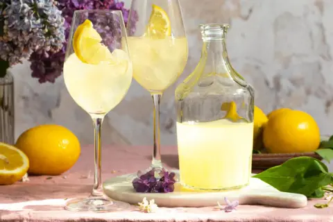 Erfrischender Limoncello Spritz mit Zitronenscheiben, Eis und Flieder.