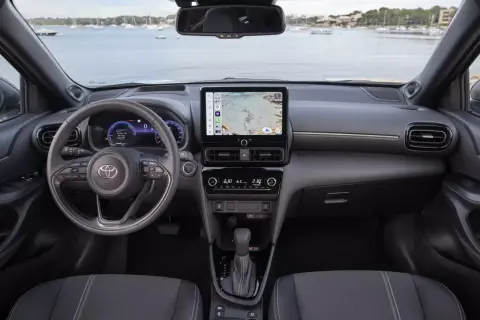Nowoczesne **toyota yaris cross wnetrze** z ekranem nawigacji i cyfrowymi zegarami. Widok na kierownicę i konsolę środkową.
