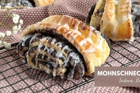 Mohnschnecken mit Zuckerguss auf einem Gitter. Ein leckeres Rezept für süße Mohnschnecken.
