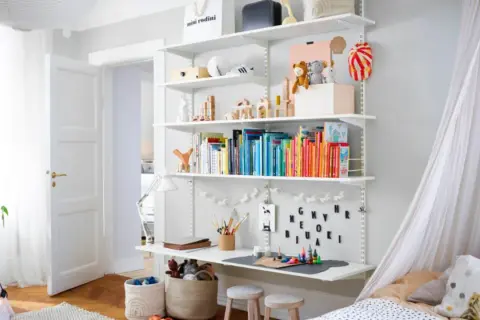 Ein schmales kleines Kinderzimmer einrichten: Bücherregal mit Spielzeug, Büchern und Bastelmaterialien. Ein Bett mit Baldachin und ein Spielzelt.