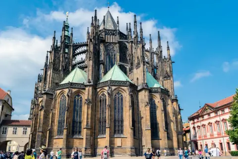 Imponente catedral gótica con sus torres y arcos detallados, bajo un cielo azul con nubes.