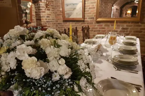 Elegancko nakryty stół z bukietem białych kwiatów i dzbankiem soku. Idealne miejsce, gdzie dobrze zjeść w Nałęczowie.