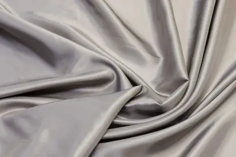Glänzender, grauer Stoff fällt in weichen Falten. Er erinnert an die glatte Oberfläche von Seide, doch ist viskose eine Naturfaser, die sich so luxuriös anfühlt.