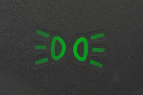 Zielony symbol świateł mijania na ciemnym tle.