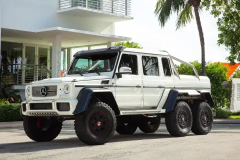 Potężny biały Mercedes G-Class 6x6 z masywnymi oponami i sześcioma kołami, gotowy na każdą przygodę.
