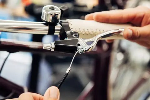 Hand replacing a bicycle's remkabel. Close-up of the brake lever and cable connection.