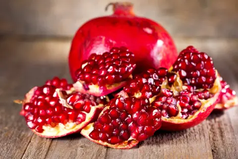 Saftige Granatapfelkerne auf Holz. Die Frucht, woher kommt der Granatapfel, stammt ursprünglich aus Persien und dem Nahen Osten.