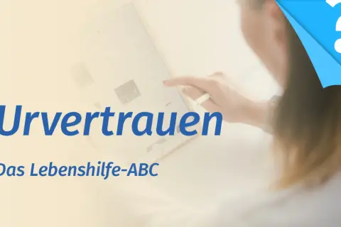 Ein Tablet zeigt Grafiken, während eine Hand mit einem Stift darauf tippt. Der Text "Urvertrauen aufbauen" und "Das Lebenshilfe-ABC" ist zu sehen.