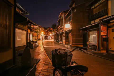 Wieczorna uliczka w tradycyjnej japońskiej dzielnicy. Drewniane domy, latarnie i rower tworzą niepowtarzalny klimat, pokazując, jak wygląda Japonia.