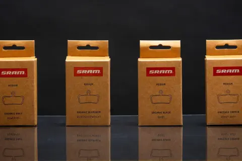 Cajas de SRAM mostrando distintos tipos de pastillas de freno: orgánicas (gris, aluminio, negra) y sinterizadas de cobre.