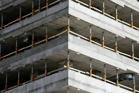 Budowa budynku z betonowymi stropami i zbrojeniem narożników wieńca, podparte tymczasowymi podporami.