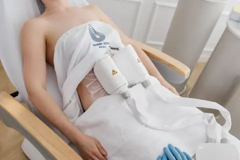 Kobieta poddana zabiegom modelującym sylwetkę, z aplikatorami na brzuchu.