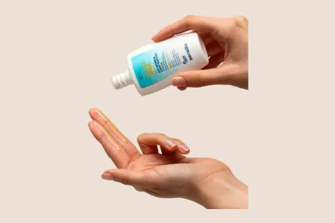Manos aplicando protector solar Sensilis. Opiniones positivas sobre su textura ligera y protección SPF 50.