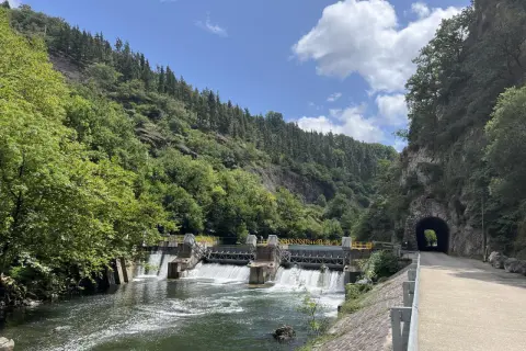 Un camino junto al río Bidasoa, con una presa y un túnel en la montaña.