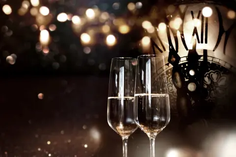 Zwei Sektgläser stehen vor einem antiken Zifferblatt. Seit wann gibt es Champagner? Seit Jahrhunderten ein Symbol für festliche Anlässe.