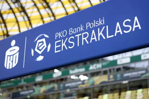 Niebieski baner z logo PKO Bank Polski Ekstraklasa na tle stadionu.
