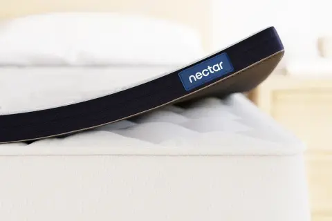 A Nectar mattress topper is shown. While toppers can improve comfort, it's worth considering if a mattress topper can cause back pain if it's too soft or firm for your needs.