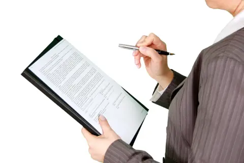 Kobieta w garniturze analizuje dokumenty, przygotowując się do kontroli nadzoru budowlanego.