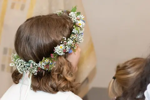 Niña con corona de flores en su cabeza, lista para su celebración de comuniones.
