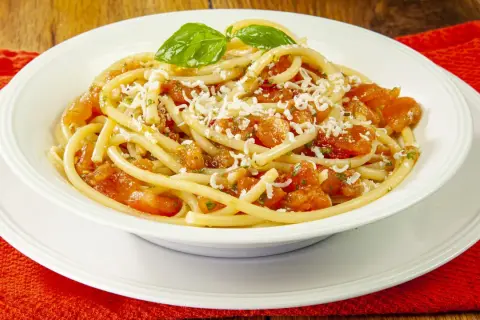 Un piatto invitante di pasta alla carrettiera, con pomodoro fresco, basilico e formaggio grattugiato.