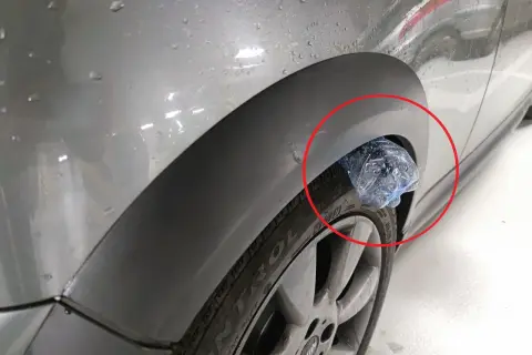 Plastikowa butelka utknęła w nadkole samochodu, tworząc nietypową ozdobę.