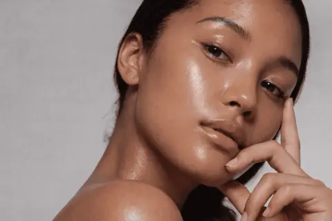 Aha, qué es esa piel radiante y jugosa. Un primer plano de una mujer con un brillo natural en su rostro y cuello.
