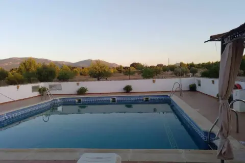 Piscina con vistas a montañas y vegetación bajo un cielo despejado.