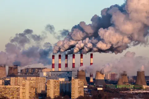 Dymiące kominy elektrowni nad miastem, świadczące o złej jakości powietrza.