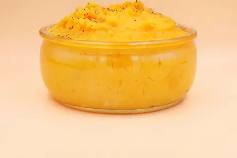 Pyszne, kremowe puree z batata w szklanym naczyniu, posypane świeżo mielonym pieprzem. Idealne jako dodatek do obiadu.