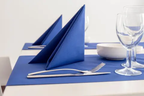 Service de table élégamment dressé avec un pliage serviette bleu vif, des couverts et des verres à vin.