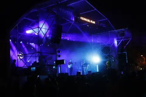 Escenario iluminado con luces azules para un concierto en la Estación del Norte de Zaragoza durante las Fiestas del Pilar.