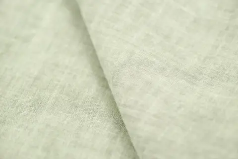 Miękki, jasnozielony len materiał z widoczną fakturą splotu.