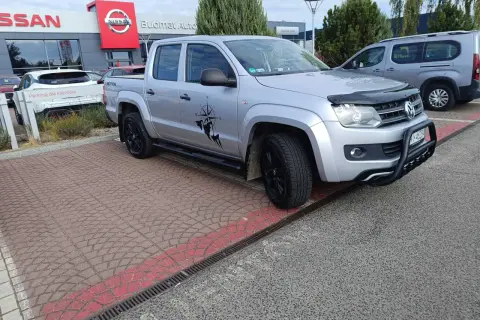Srebrny pickup z naklejką kompasu i postacią, gotowy do podróży. Idealny do pkd wynajem samochodów.