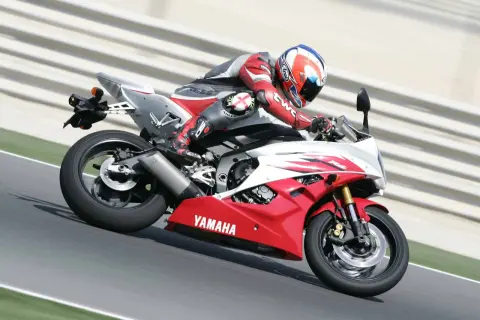 Motocyklista w czerwonym kombinezonie śmiga na torze na czerwono-białej Yamasze R6. Od ilu lat można robić prawo jazdy na motor 600? Od 20.