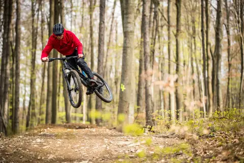Mountainbiker springt in einem Bikepark in Tschechien über eine Schanze.