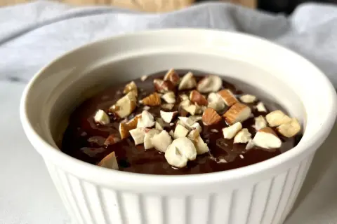 Czekoladowy deser low carb posypany orzechami w białej miseczce.