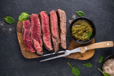 Perfekt gegrilltes Steak, in Scheiben geschnitten, mit Kräutersauce und frischem Spinat. Ein Genuss für jeden Fleischliebhaber.