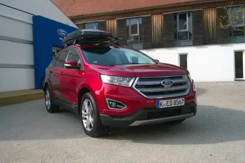 Czerwony Ford Edge z boxem dachowym, idealny na rodzinne wyjazdy. Sprawdź jego imponujące ford edge wymiary!